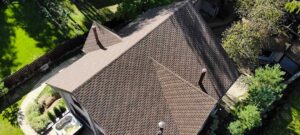 A close view of a house roof showing both asphalt shingles and standing seam metal panels side by side.