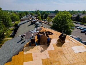 Homeowner viewing roof shingles and attic ceiling for storm damage during a seasonal inspection.